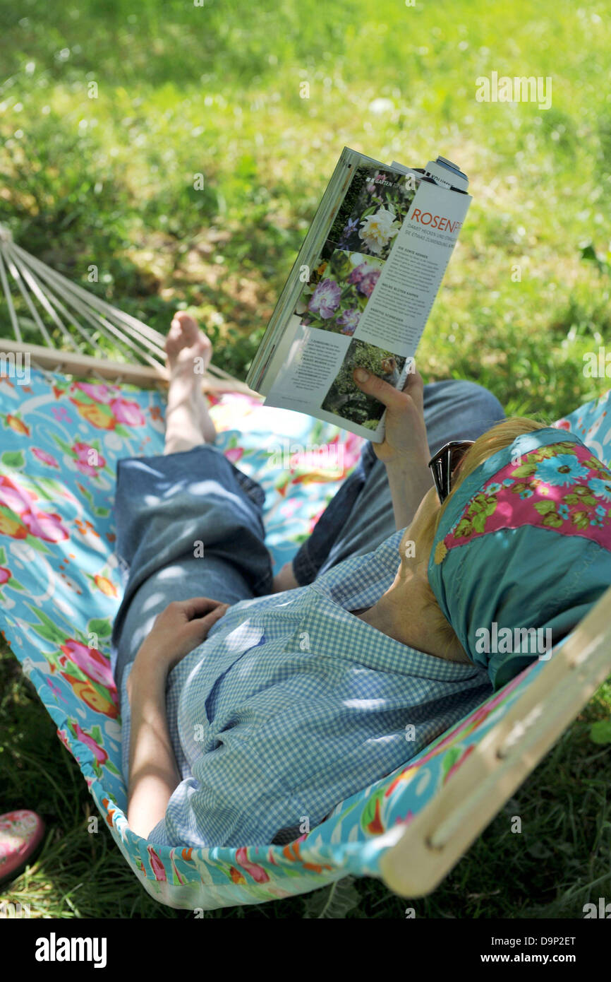 Woman lying in hammock reading magazine Stock Photo - Alamy