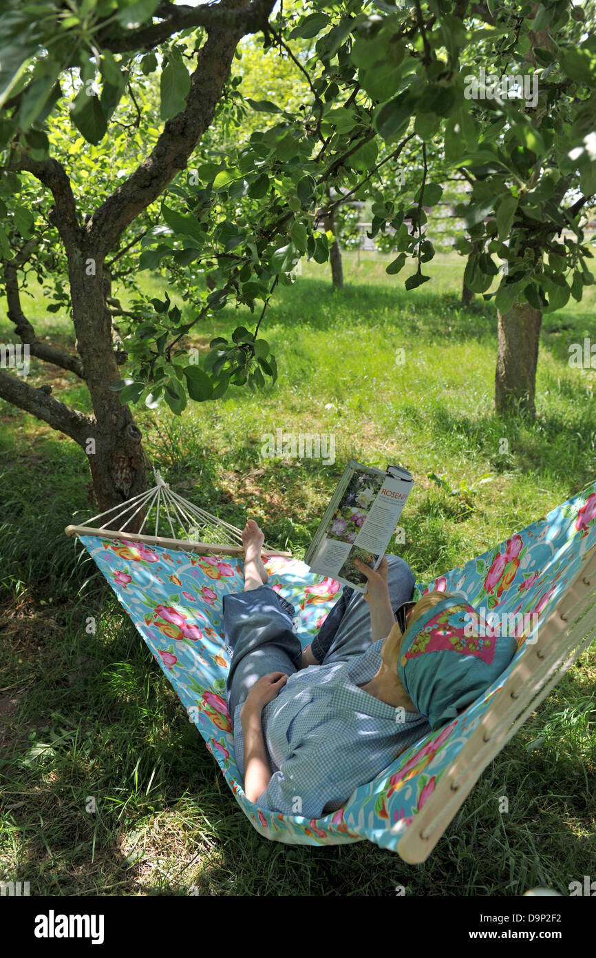 Woman lying in hammock reading magazine Stock Photo - Alamy