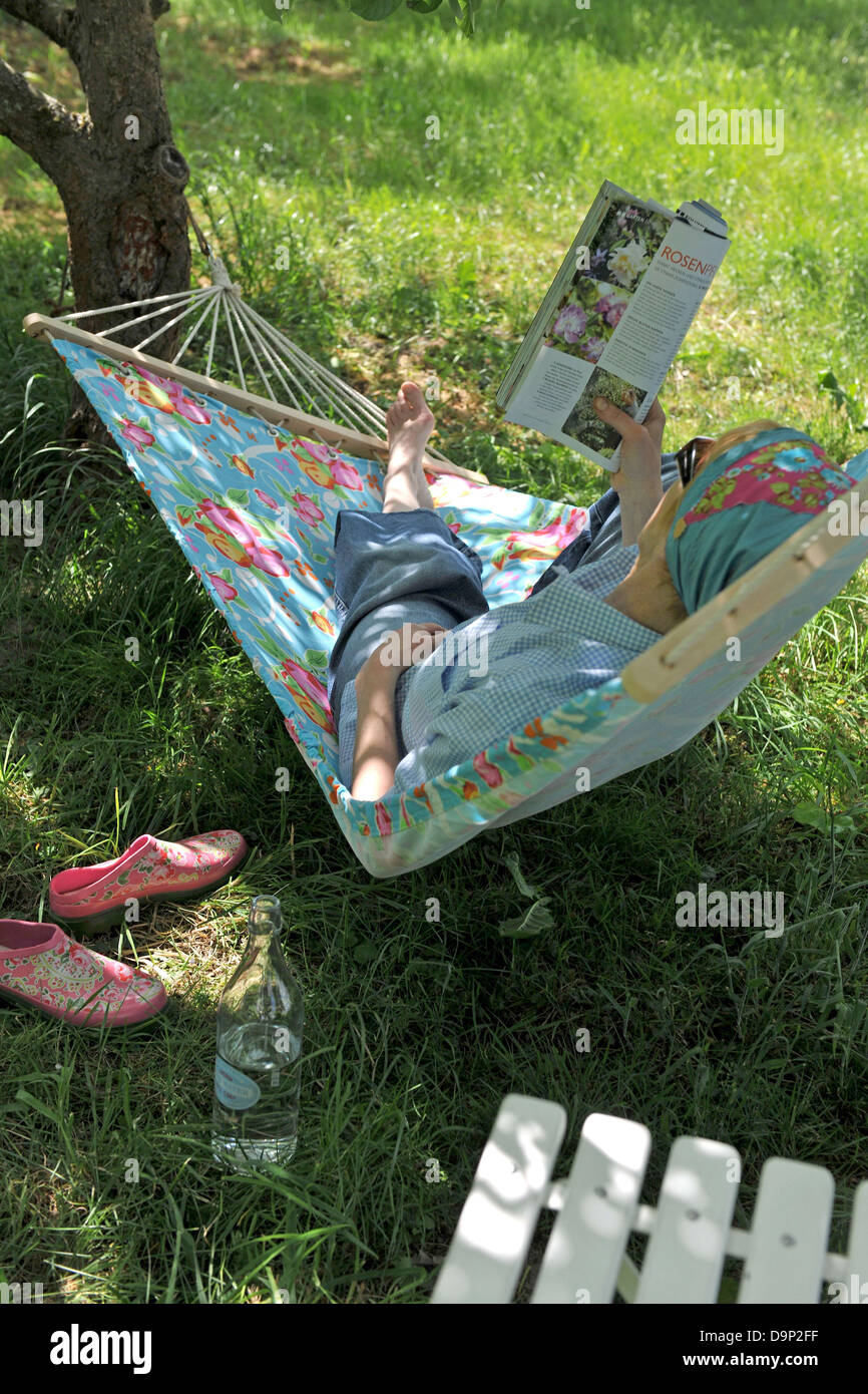 Woman lying in hammock reading magazine Stock Photo - Alamy