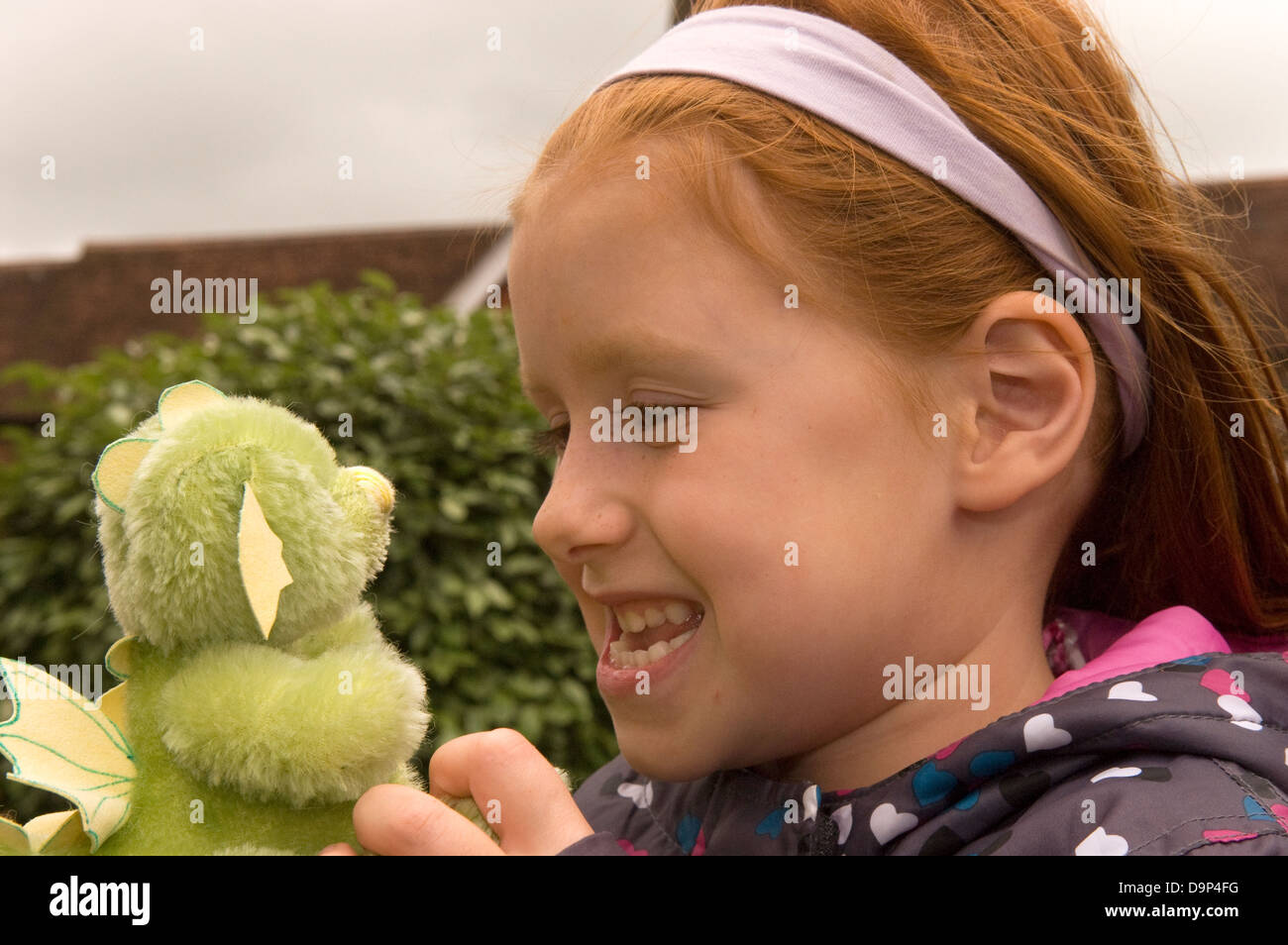 6 year old girl with a hand-made green dragon at a Teddy Bear Festival, Alton, Hampshire, UK. Stock Photo