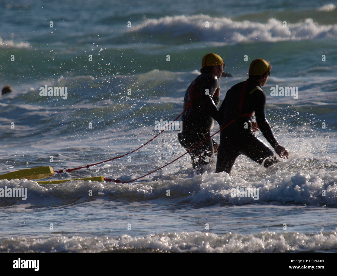Two surf life savers heading into the sea during a training session, Bude, Cornwall, UK 2013 Stock Photo