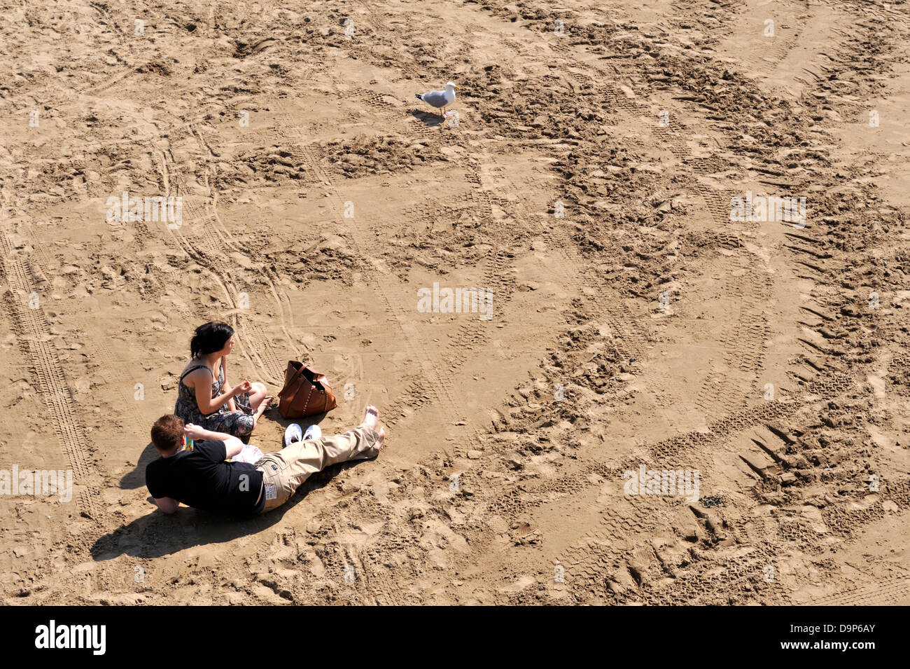 Couple sitting on sandy beach Stock Photo