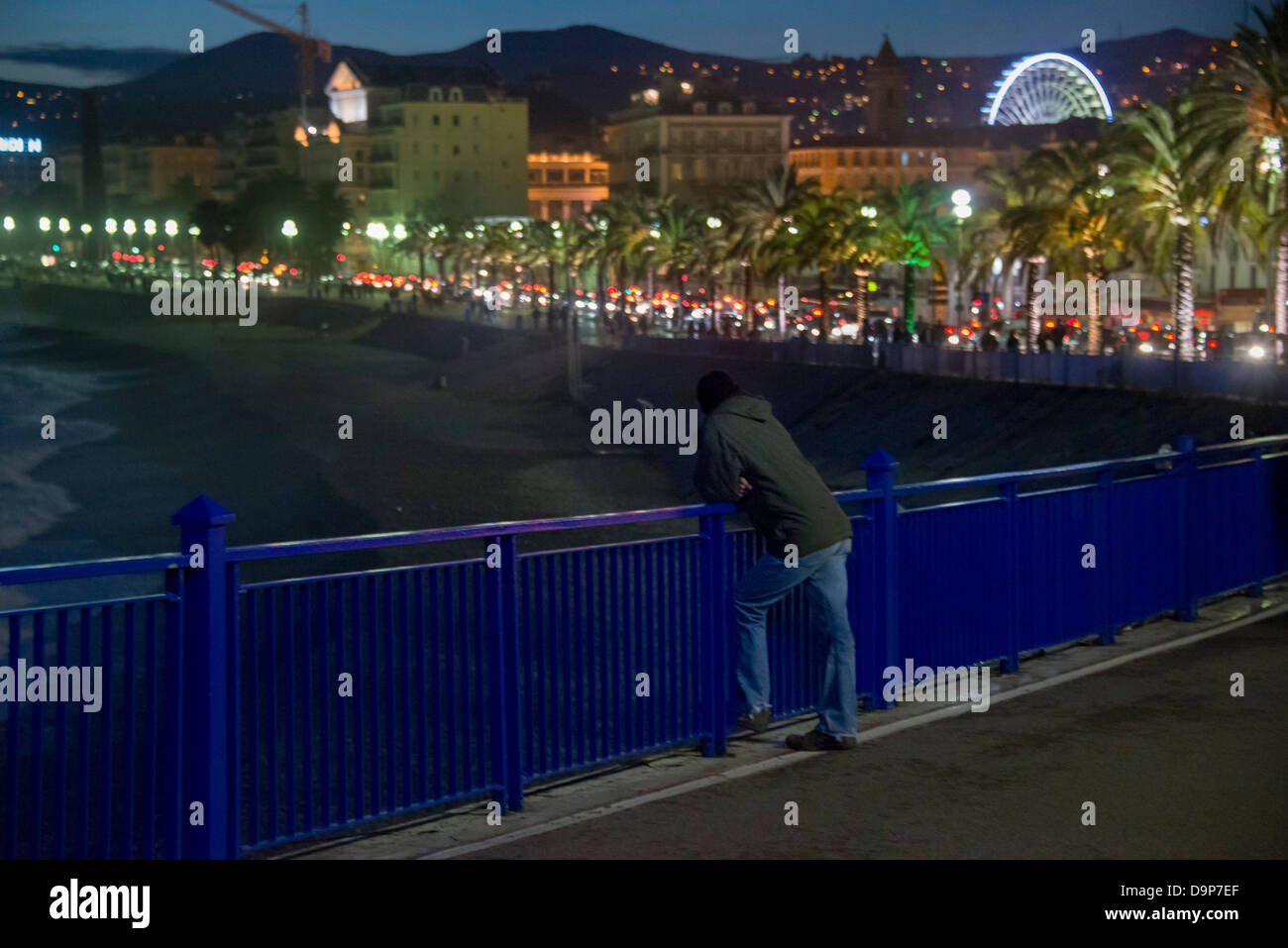 A man looking out over the  night-time view of  Promenade des Anglais in Nice France Stock Photo