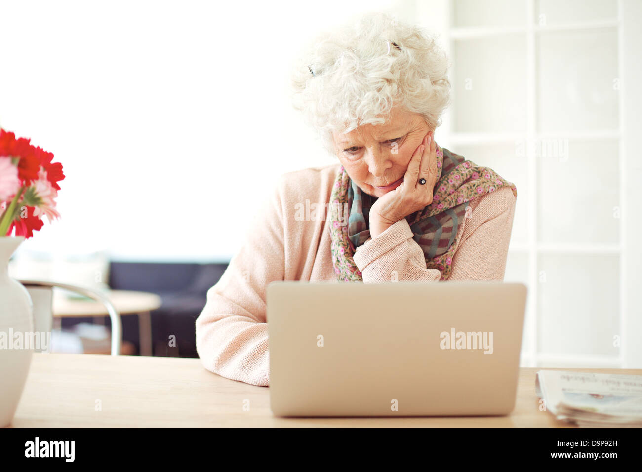 Busy senior woman at home reading something on her laptop Stock Photo