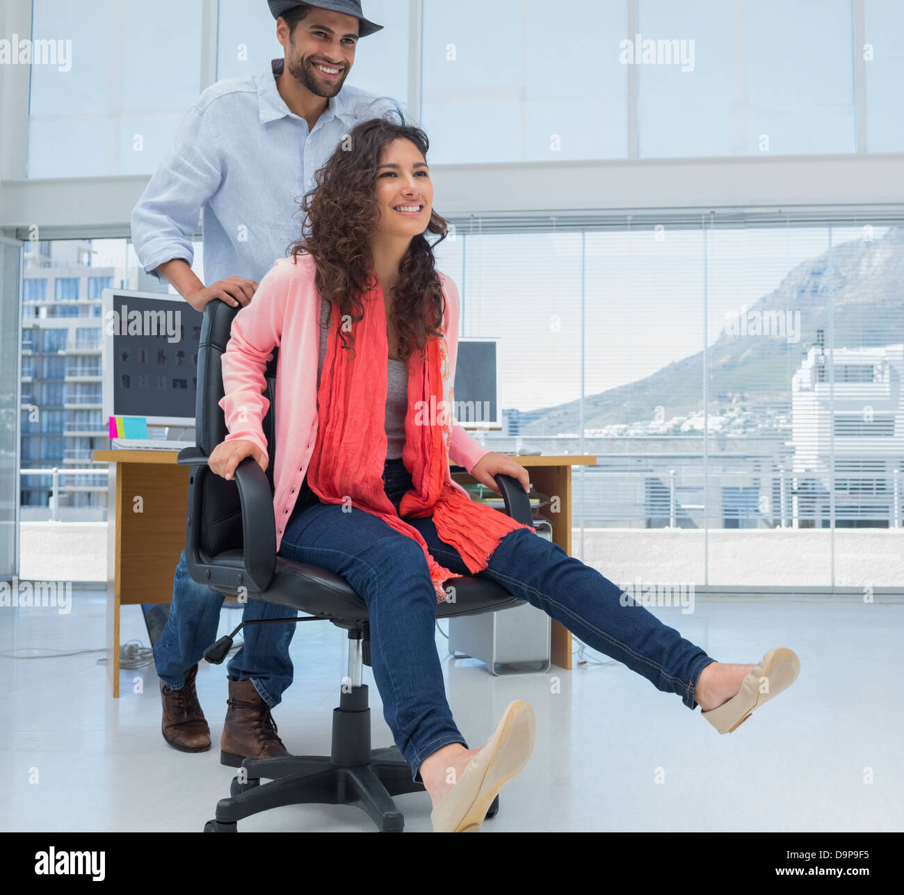Creative business colleagues having fun on an office chair Stock Photo