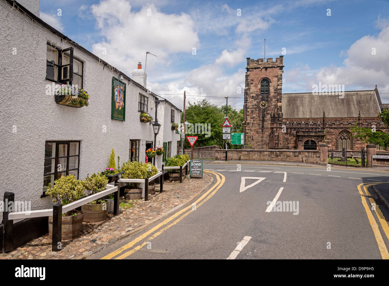 The church of St. Laurence in Overton a suburb of Frodsham seen past the Ring O' Bells public house. Stock Photo