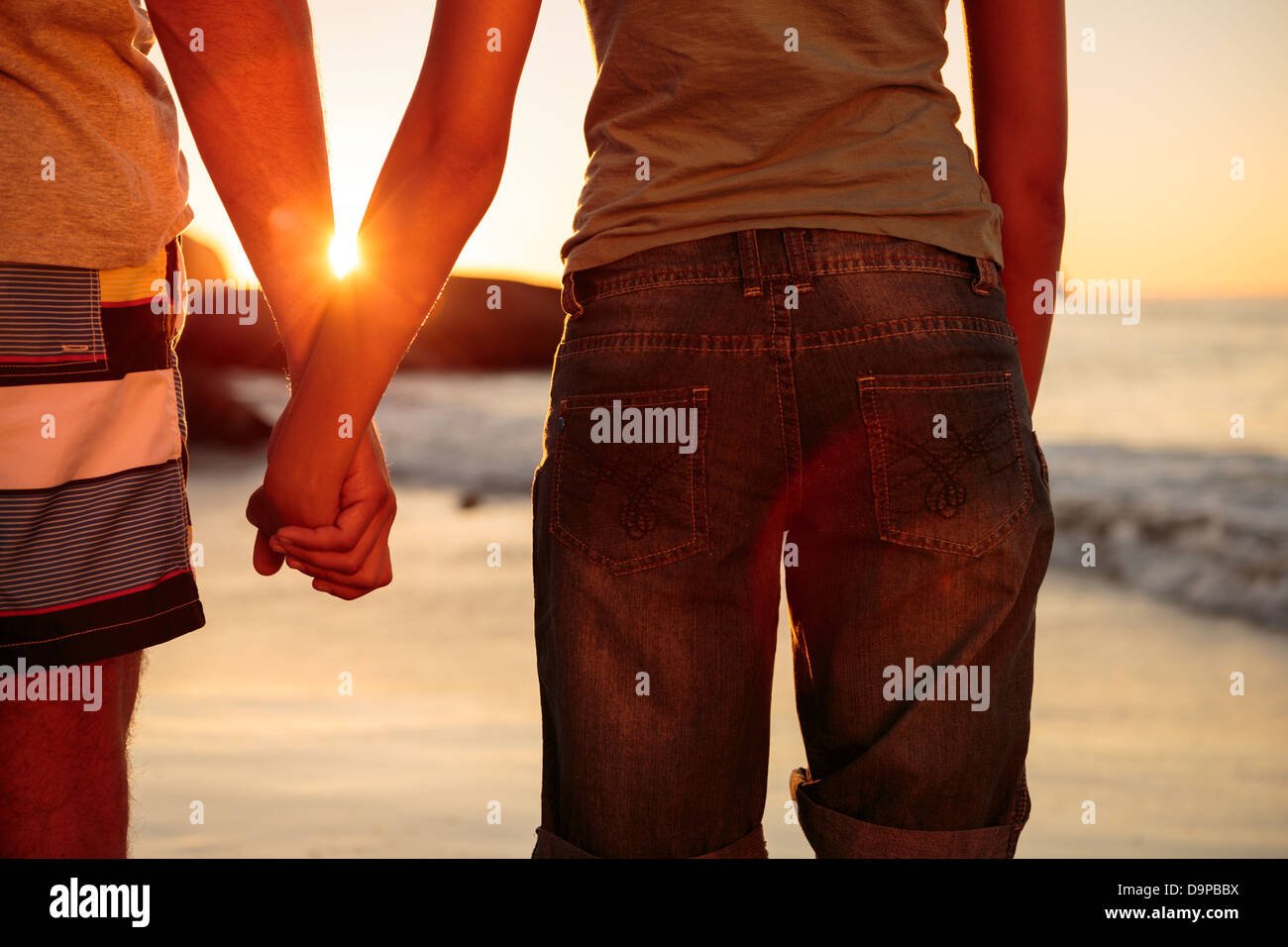 Rear view of a couple hand in hand walking on the beach Stock Photo - Alamy