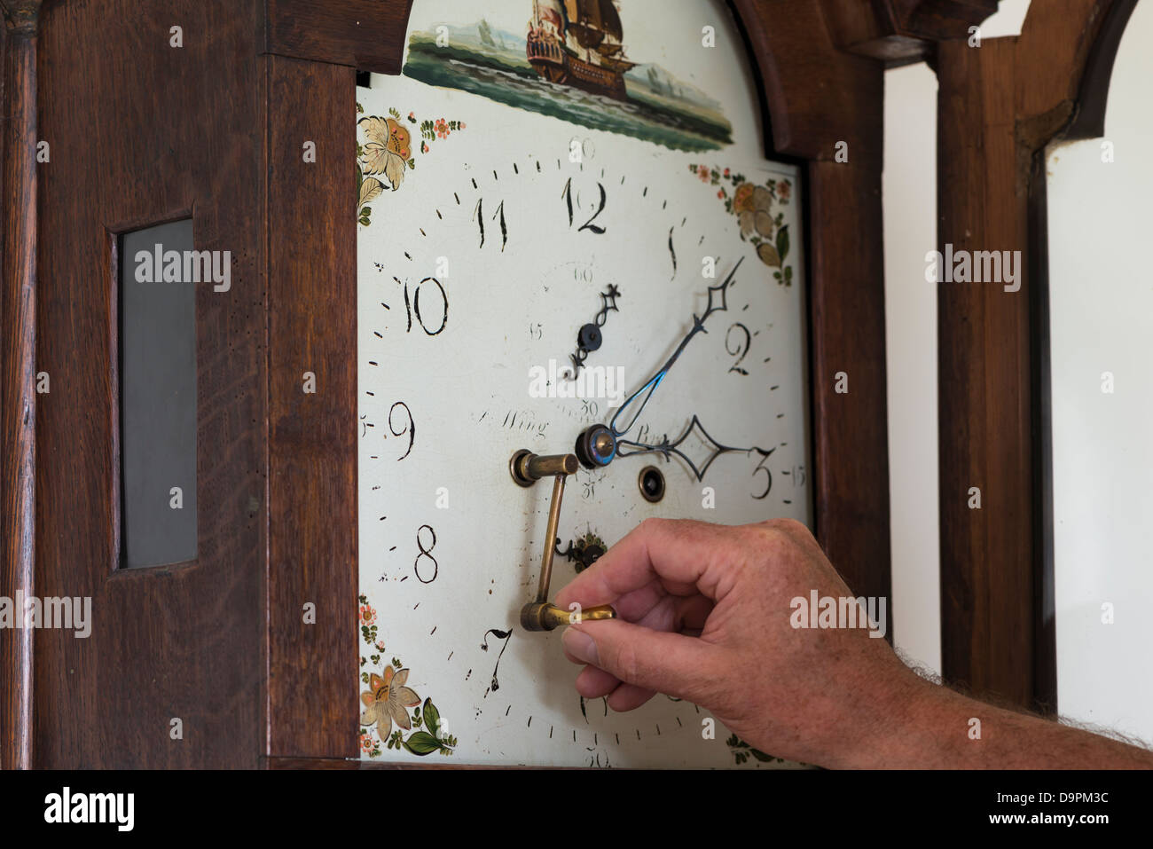Winding up a grandfather clock Stock Photo
