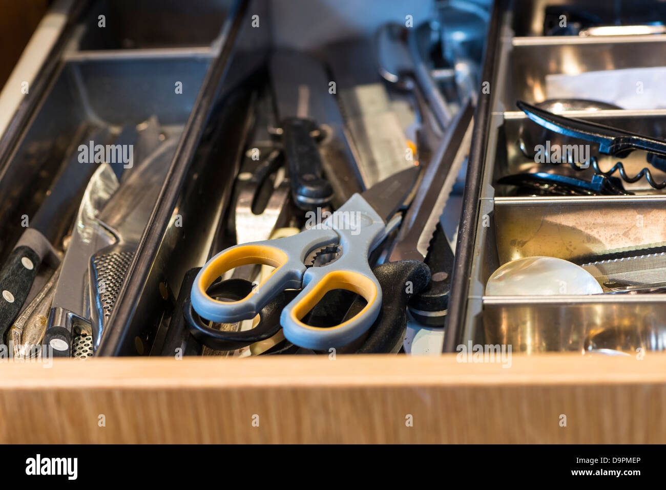 A kitchen drawer containing sharp objects dangerous for children Stock Photo