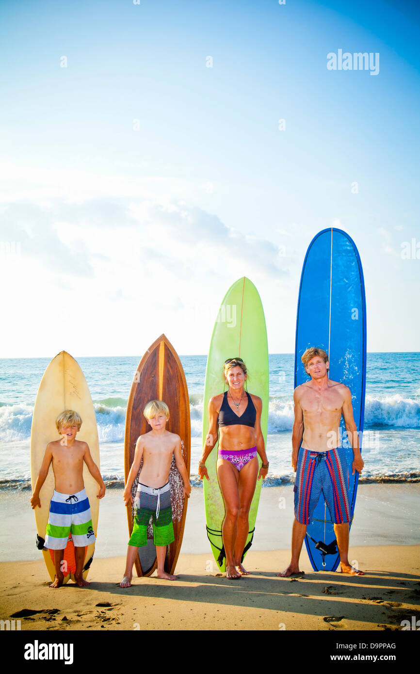 Family standing on beach with surfboards Stock Photo