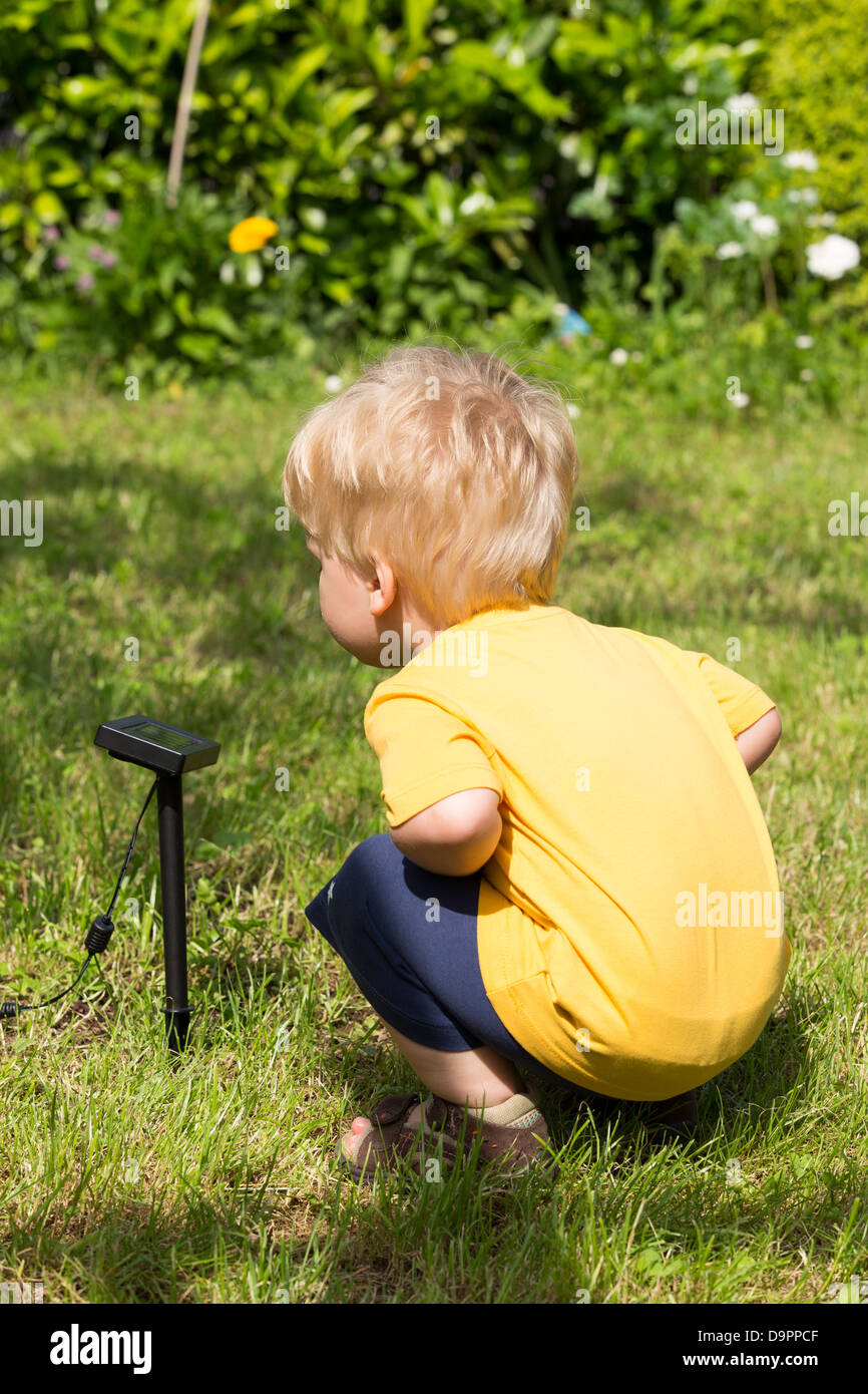 Little child interested by solar battery in his garden. Stock Photo