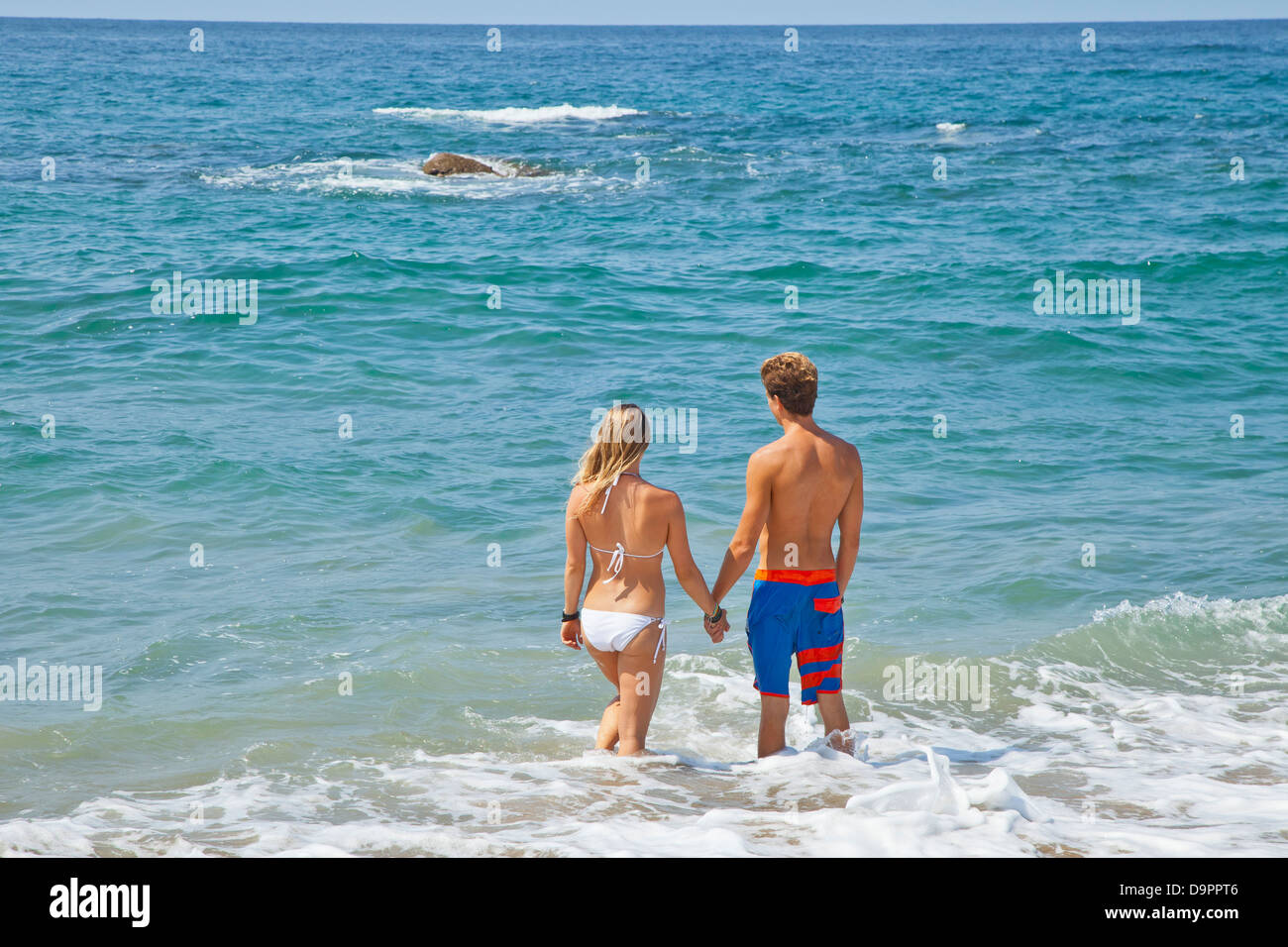 Young man and woman standing in surf Stock Photo