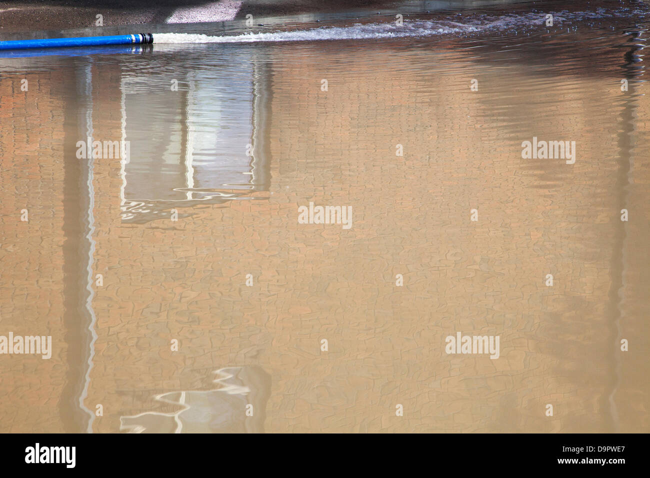 Hose line drains water pumped from flooded basement of apartment into a