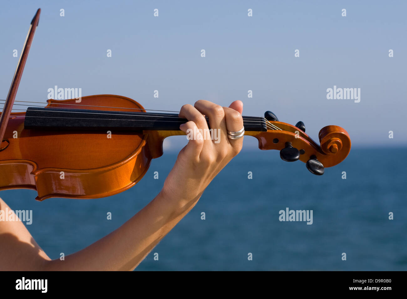 female violinist playing violin on beach Stock Photo