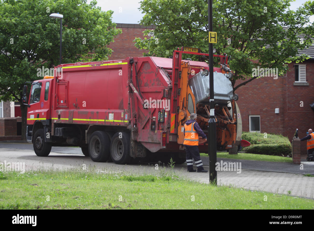 bin lorry / refuse collection. Image shows bin man loading a refuse bin into the garbage truck. Stock Photo
