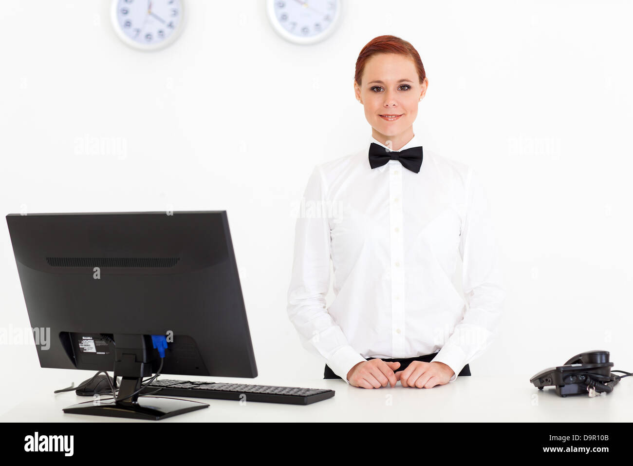 pretty young receptionist standing by hotel reception Stock Photo