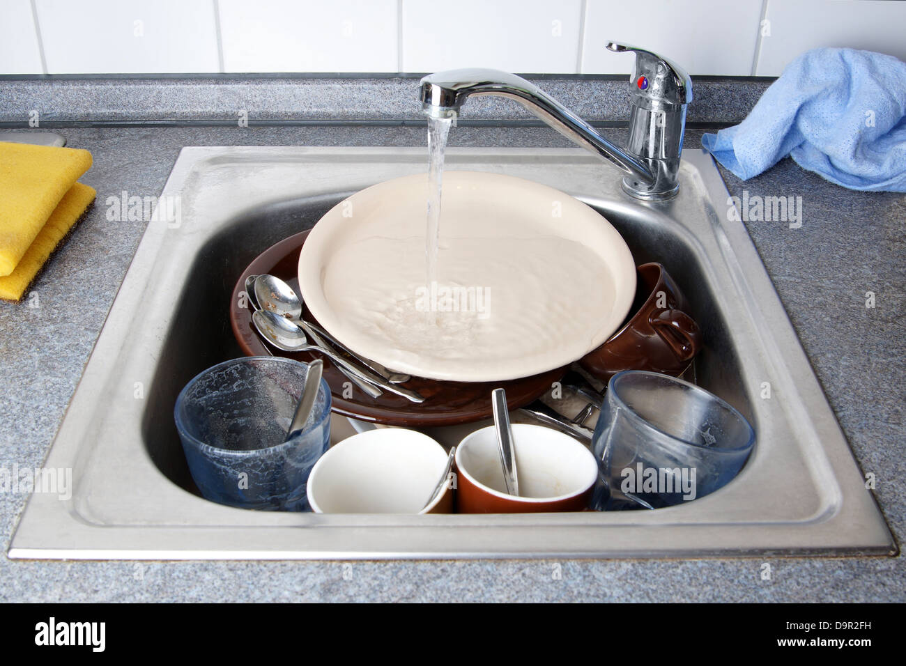pile of dirty dishes in kitchen sink with running water Stock Photo Alamy