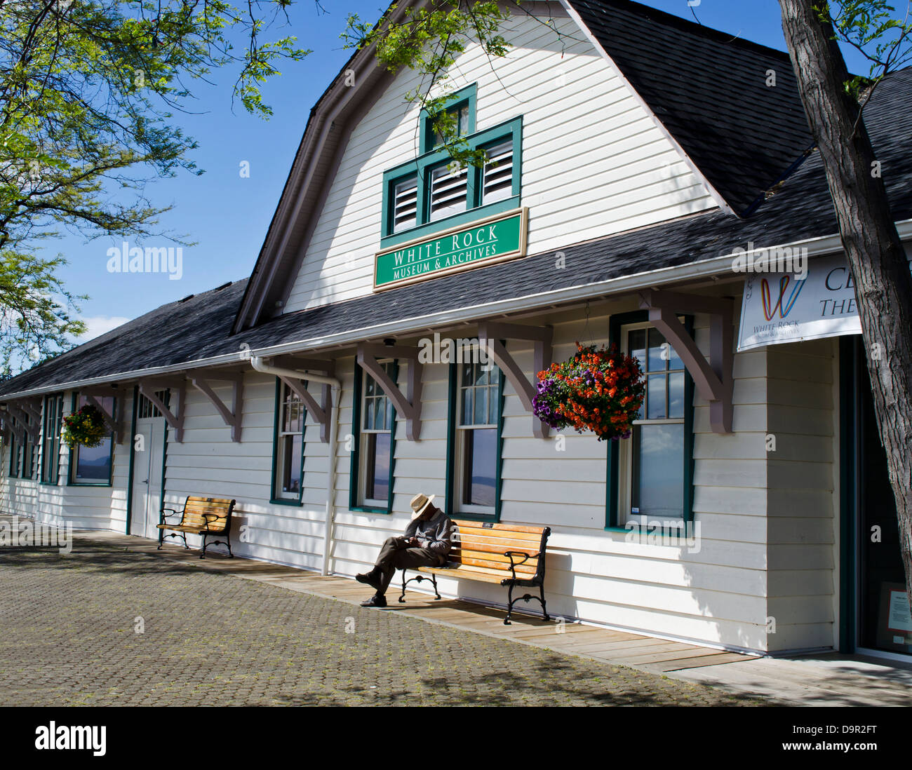 Man on a bench taking a nap in the sunshine by the White Rock train museum in British Columbia, Canada. Stock Photo