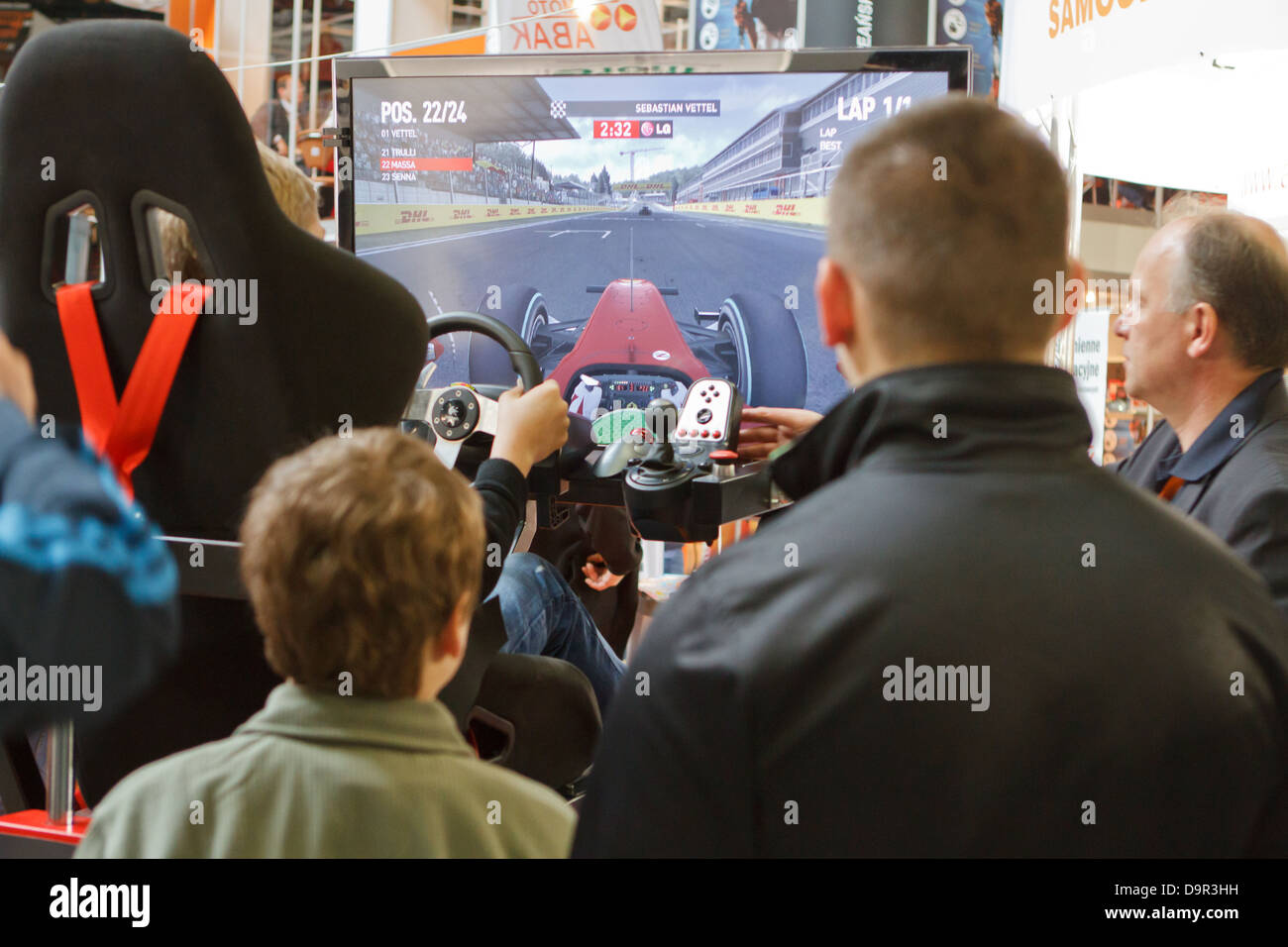 Visitors of ProfiAuto Show 2013, Katowice, Poland, watching on driving simulator. Stock Photo