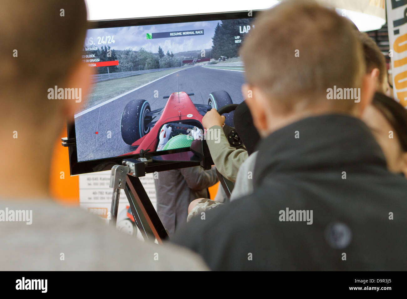 Visitors of ProfiAuto Show 2013, Katowice, Poland, watching on driving simulator. Stock Photo
