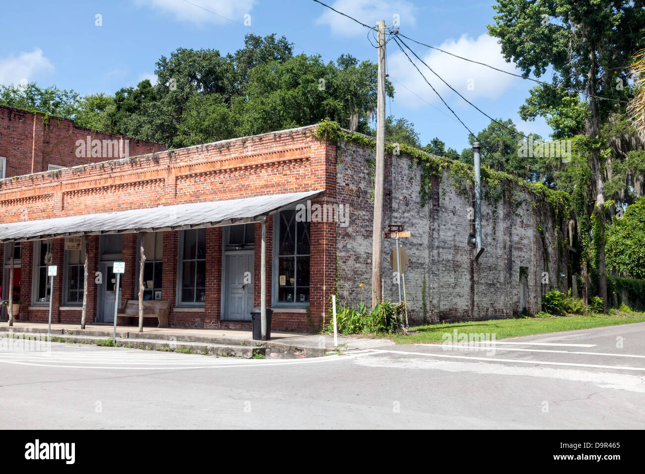Old single-story brick commercial building with porch covering the sidewalk located in historic district of Micanopy, Florida. Stock Photo