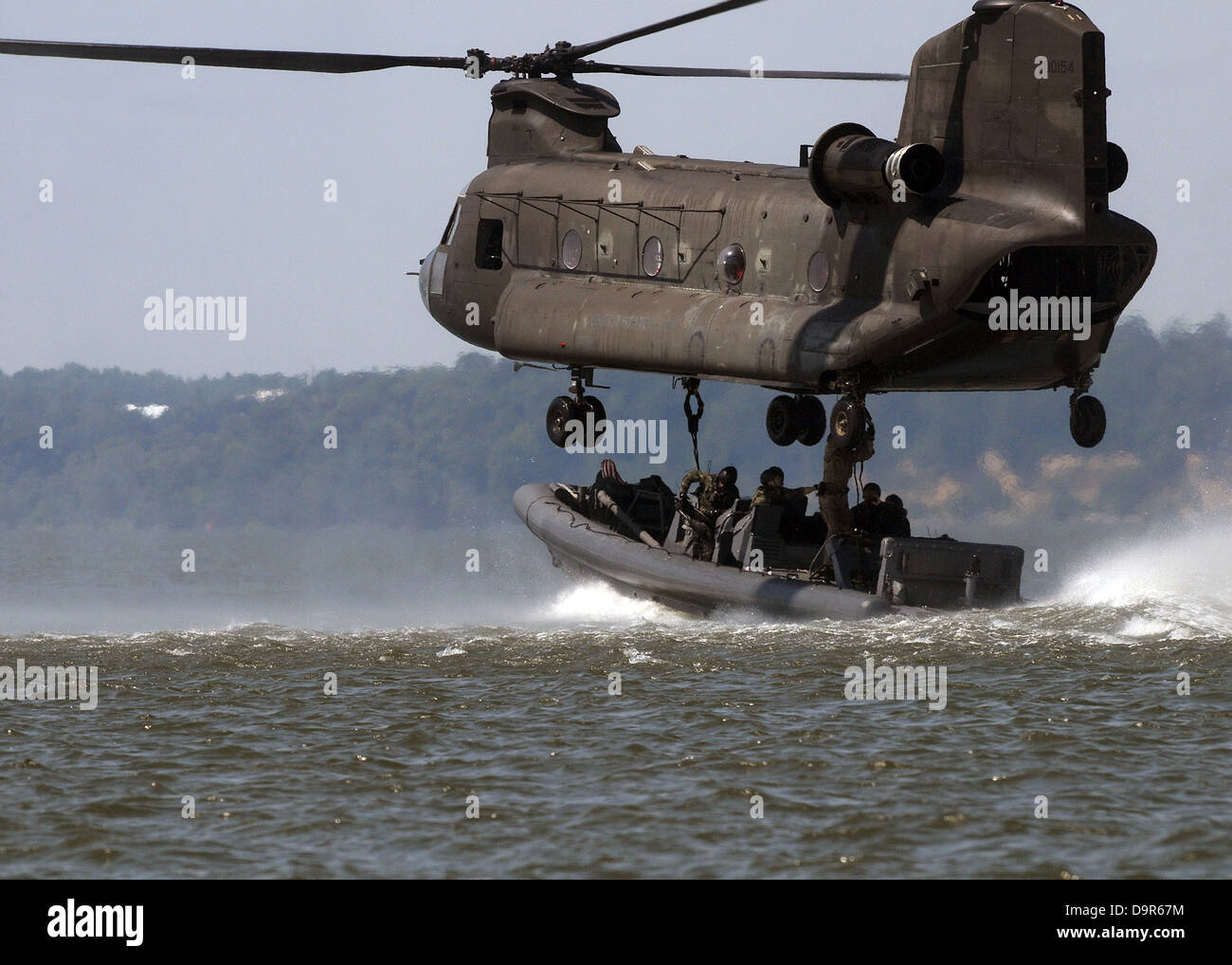 US Navy SEALS in a Special Warfare Combatant-craft attach a naval special warfare 11-meter rigid-hull inflatable boat to an Army CH-47 Chinook helicopter during a training exercise July 16, 2008 at Ft. Eustis, VA. Stock Photo