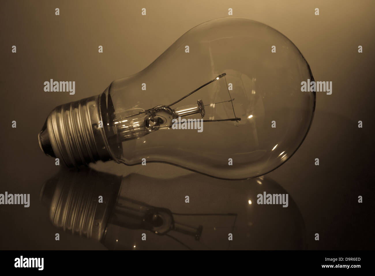 Clear light bulb laying on its side on reflective surface Stock Photo