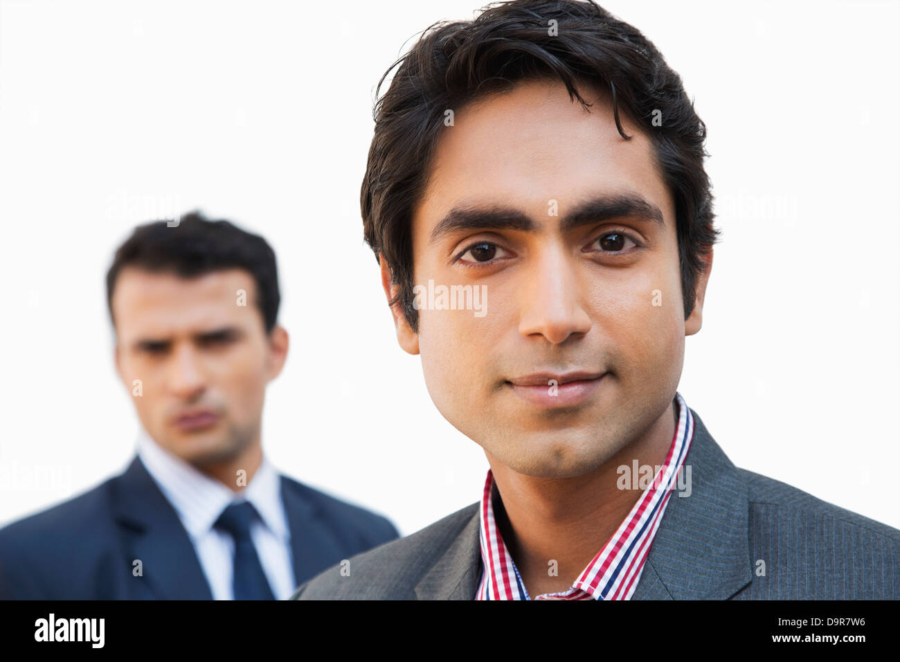 Close-up of a businessman smiling with his colleague in the background Stock Photo