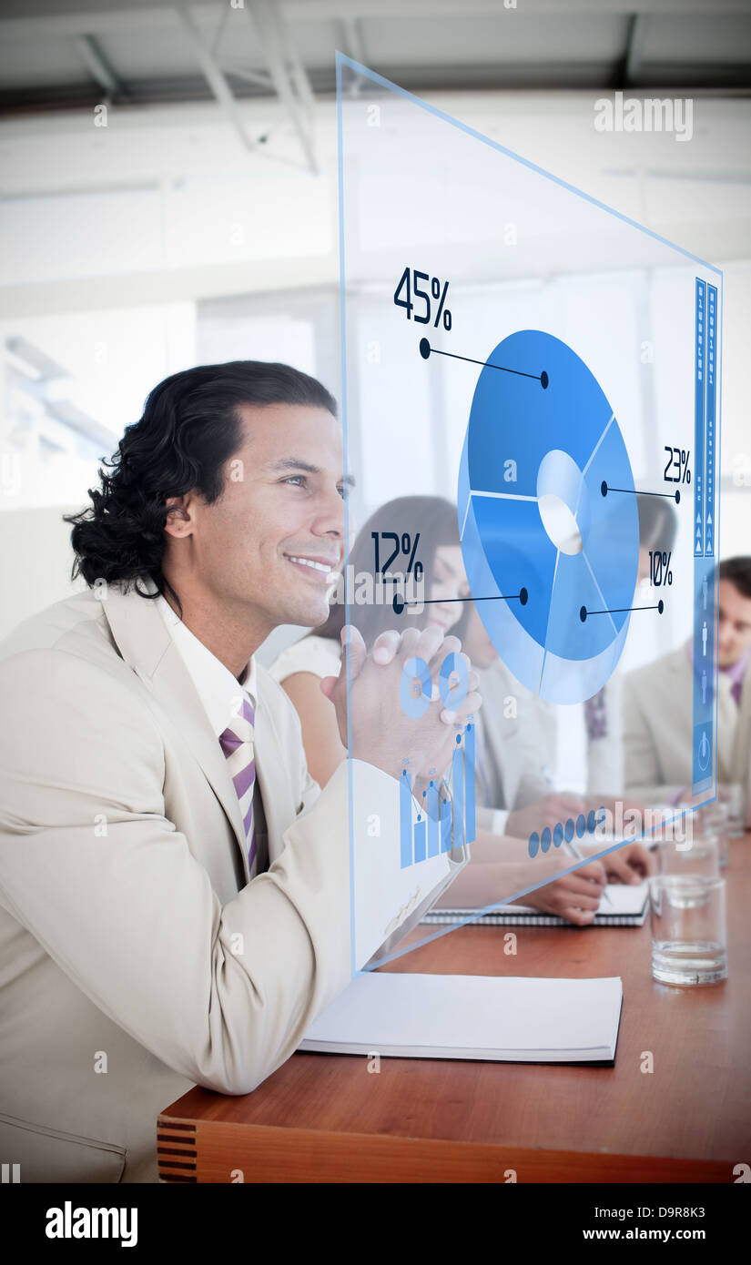 Smiling businessman looking at blue pie chart interface Stock Photo