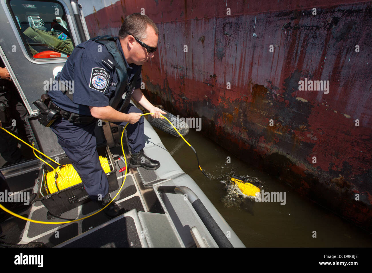 001 CBP Officers deploy underwater robot below a ship. Stock Photo