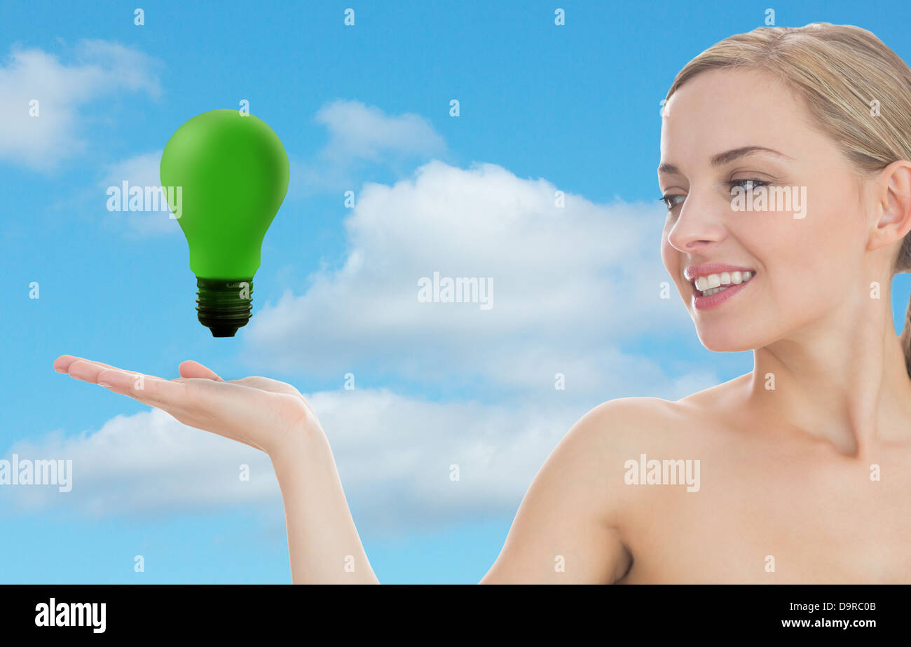 Smiling woman looking at green light bulb Stock Photo