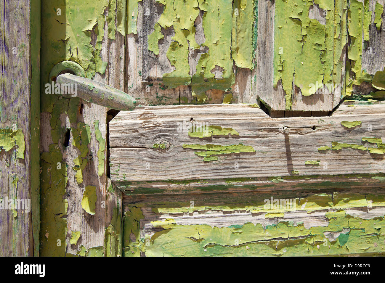 Green paint flakes on a door baking in the sun in Megalochori on the island of Santorini in Greece. Stock Photo