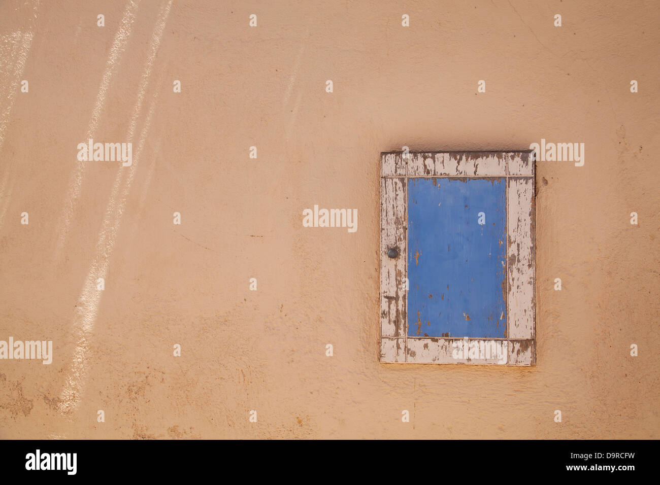 A small window hatch is highlighted with blue and white paint in Megalochori on the Island of Santorini in Greece. Stock Photo