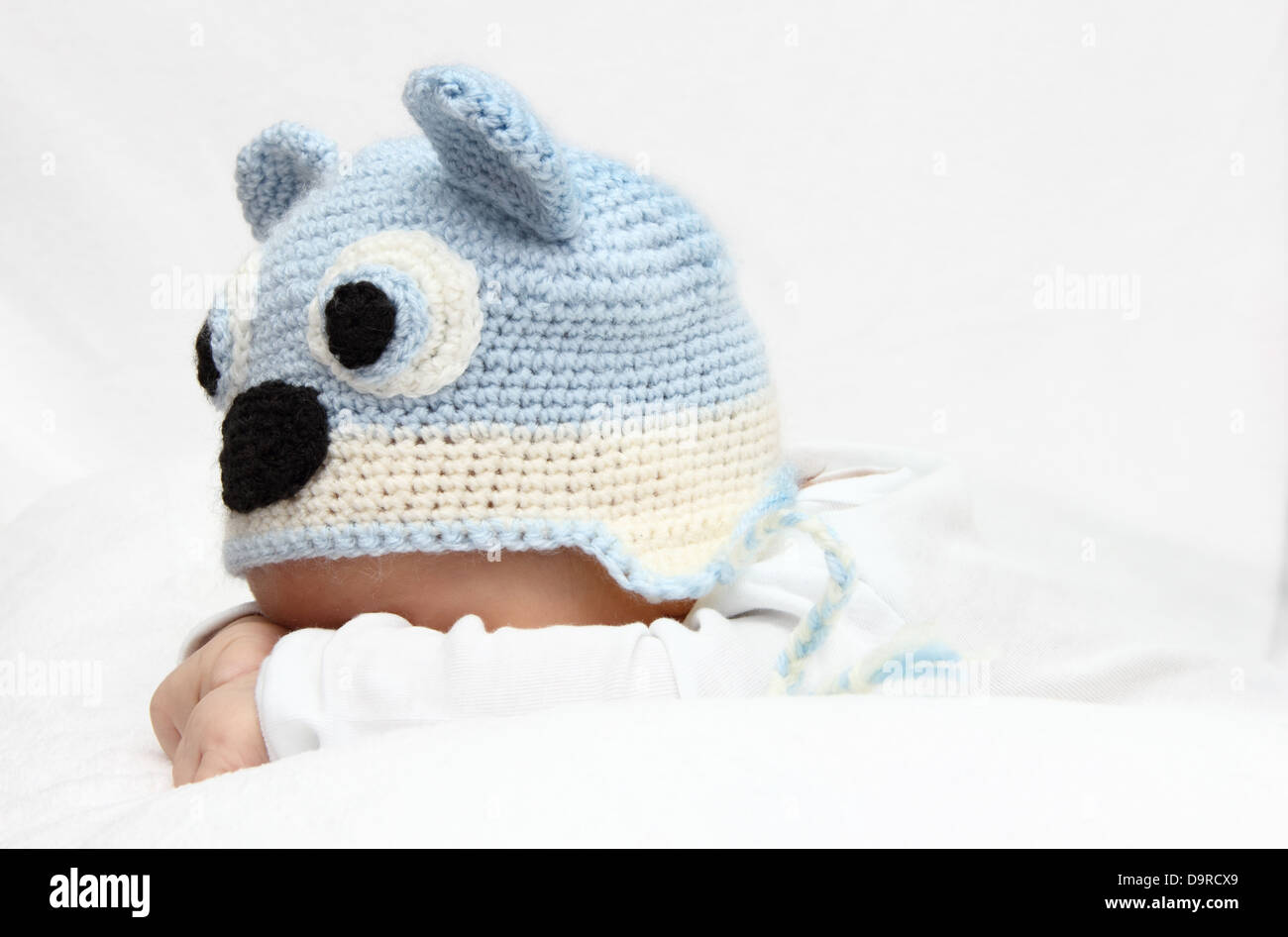 Baby with a knitted blue hat baby on stomach Stock Photo