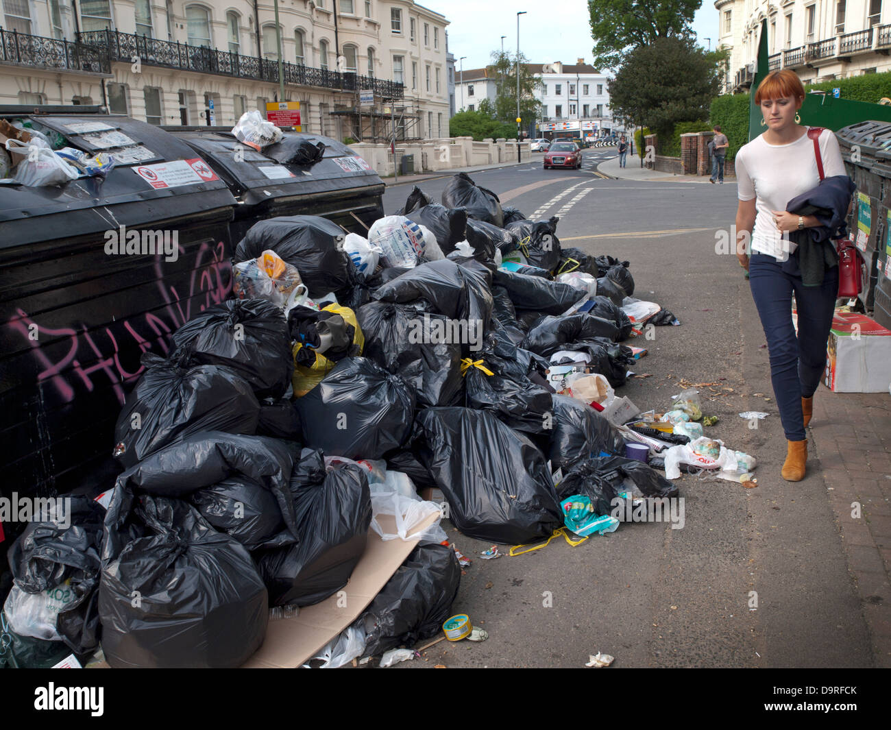 Brighton residents walk past ever growing piles of rubbish on the