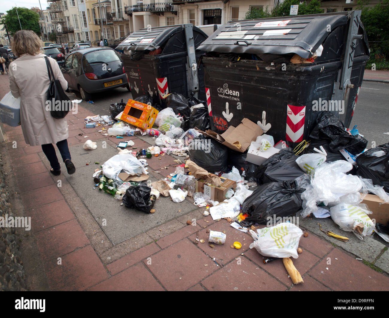 Brighton residents walk past ever growing piles of rubbish on the