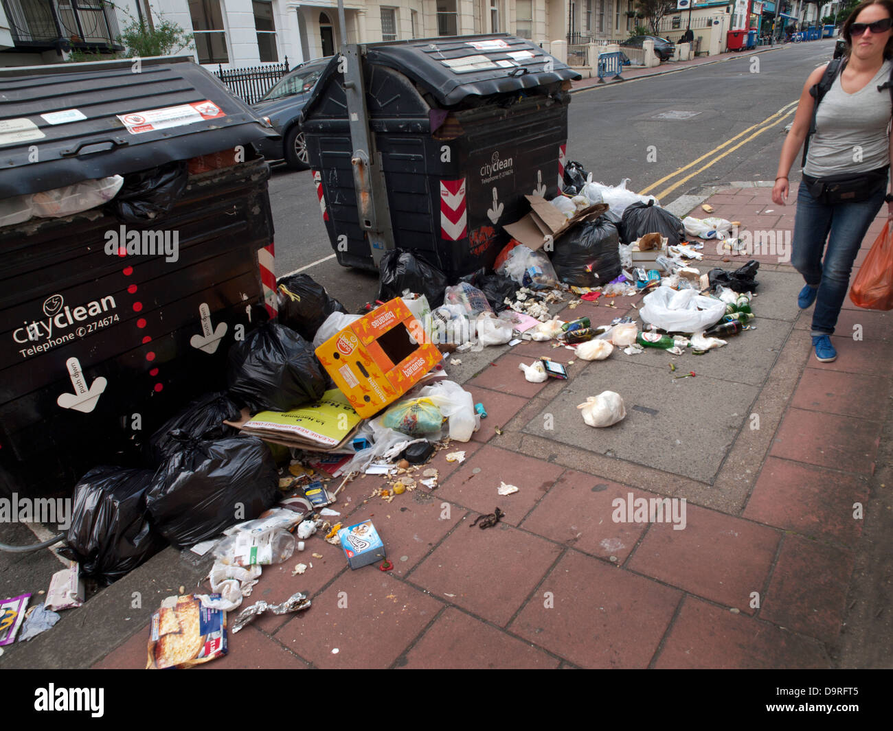 Brighton residents walk past ever growing piles of rubbish on the