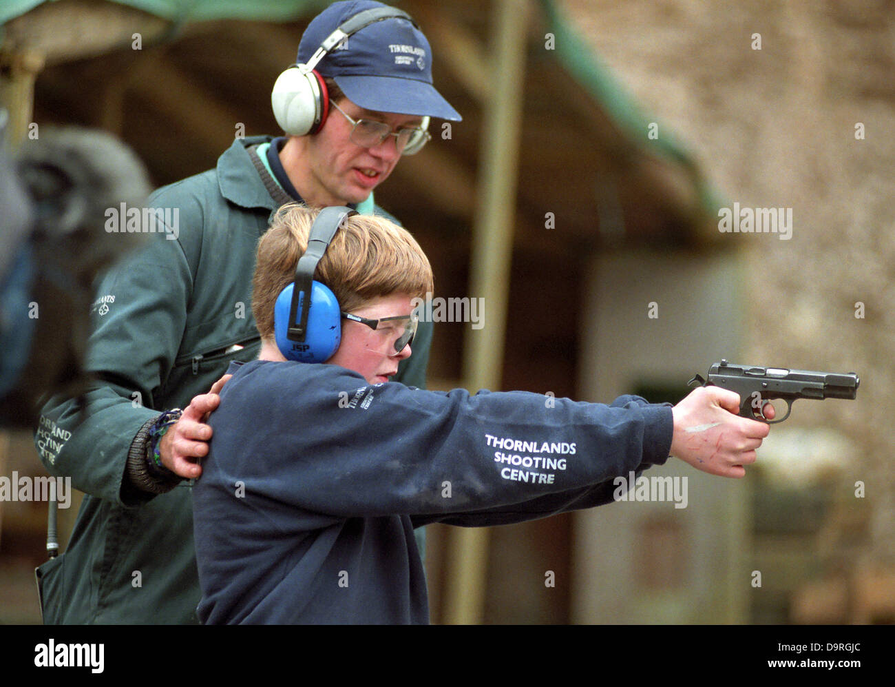 Youngster firing a hand gun on a range. Stock Photo