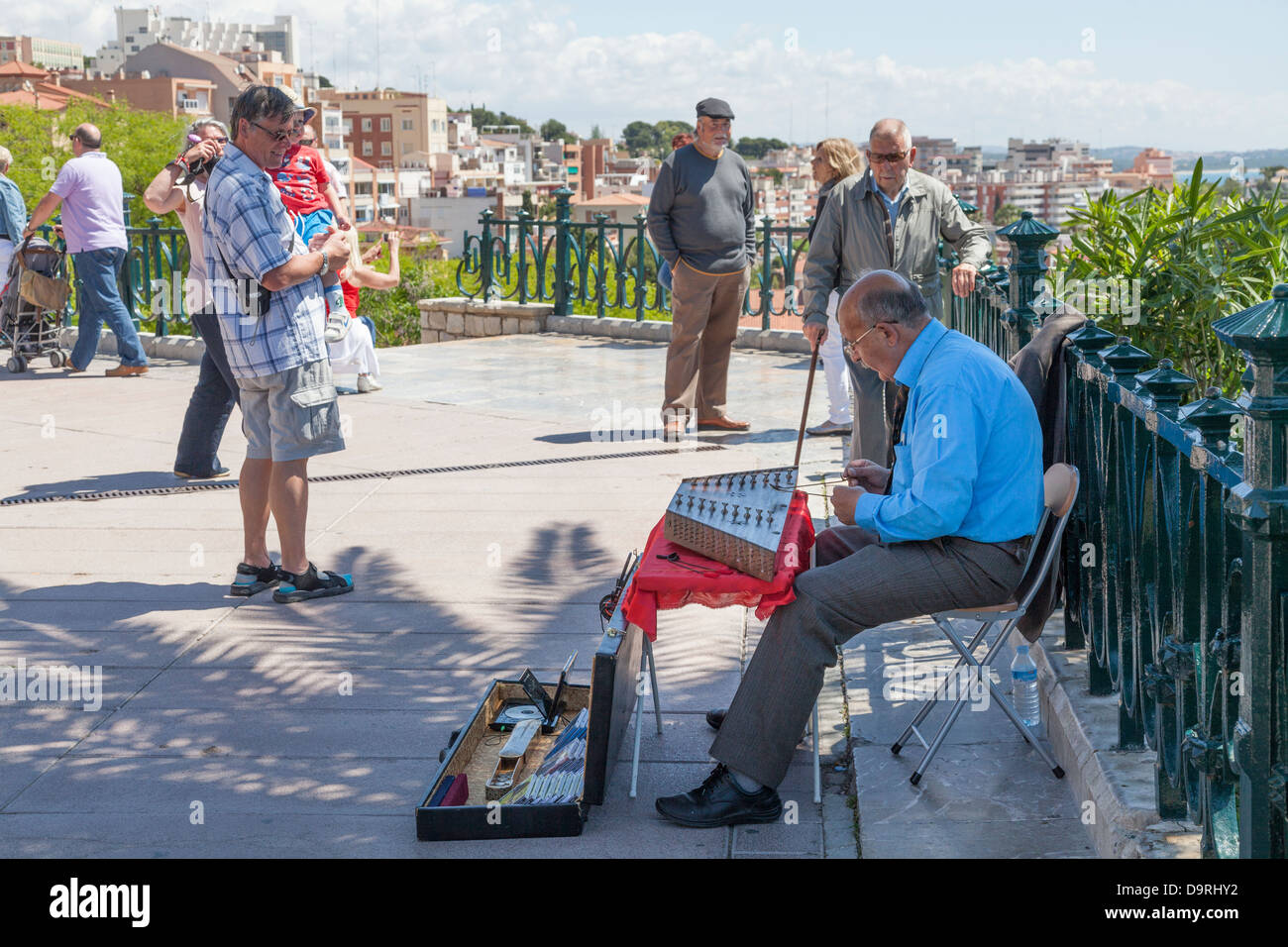 Tourists watching a busker playing a Santoor Dulcimer at Tarragona, Spain. Stock Photo