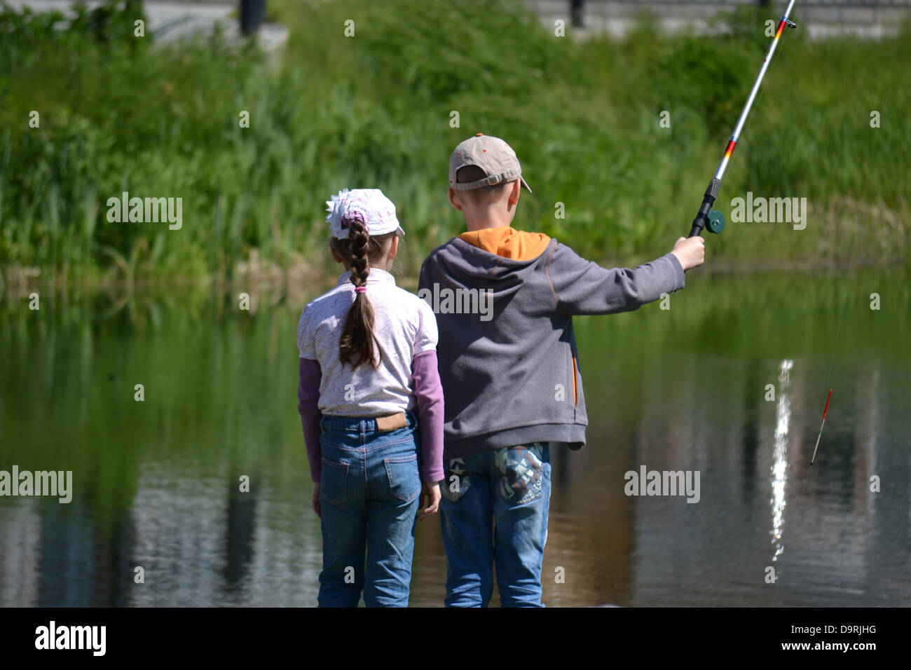 https://c8.alamy.com/comp/D9RJHG/the-girl-and-the-boy-with-a-rod-stand-on-the-bank-of-a-pond-D9RJHG.jpg