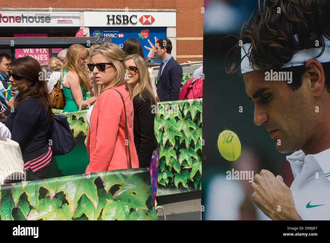 Wimbledon, England, 25th June 2013 - Day 2 of the annual lawn tennis championships and spectators queue for taxies be a poster of past Mens' champion Roger Federer outside the mainline and underground (subway) station in the south London suburb. The Wimbledon Championships, the oldest tennis tournament in the world, have been held at the nearby All England Club since 1877. Stock Photo
