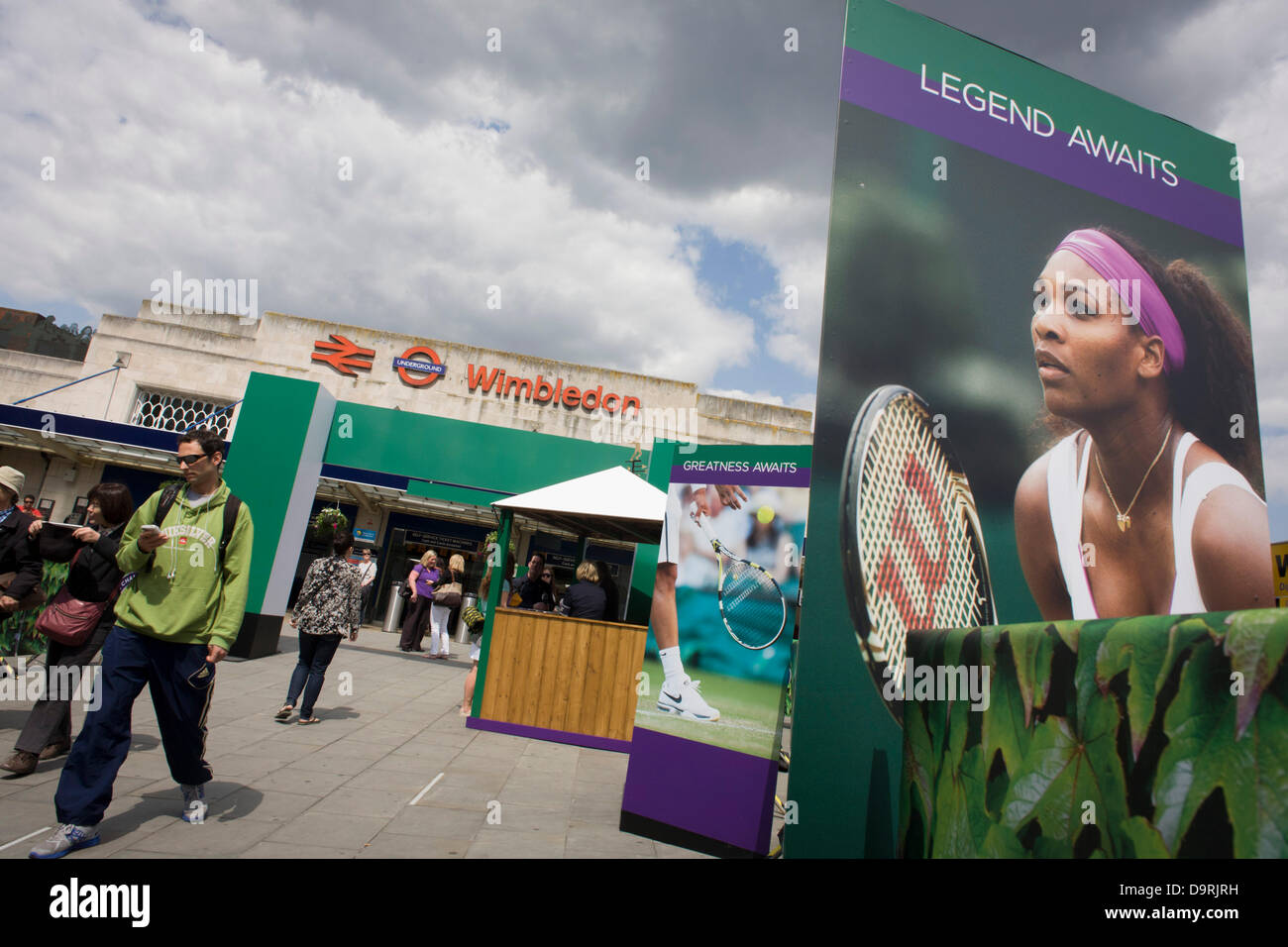 Wimbledon, England, 25th June 2013 - Day 2 of the annual lawn tennis championships and spectators mingle with locals near a large billboard of Ladies champion, Serena Williams seen outside the mainline and underground (subway) station in the south London suburb. The Wimbledon Championships, the oldest tennis tournament in the world, have been held at the nearby All England Club since 1877. Stock Photo