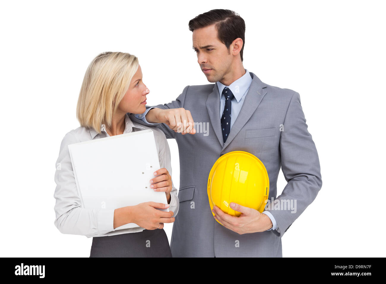 Architects with plans and hard hat looking at each other Stock Photo