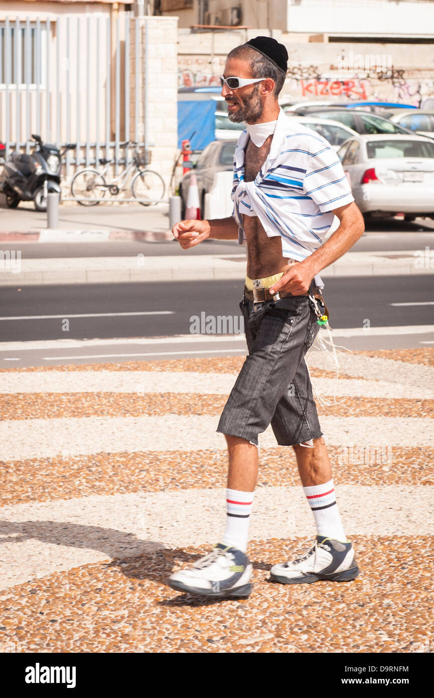 Israel Tel Aviv devout orthodox Jew with tzitzit skullcap skull cap kippah kippa kipa yarmulke walking to Gay Pride Party promenade street scene Stock Photo