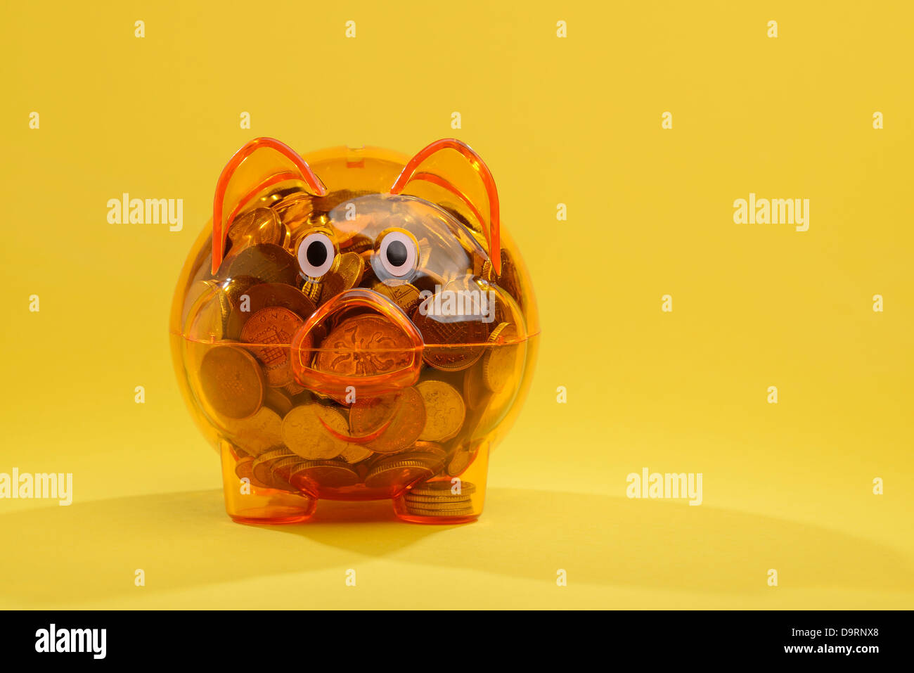 Clear plastic piggy bank filled with UK sterling coins Stock Photo