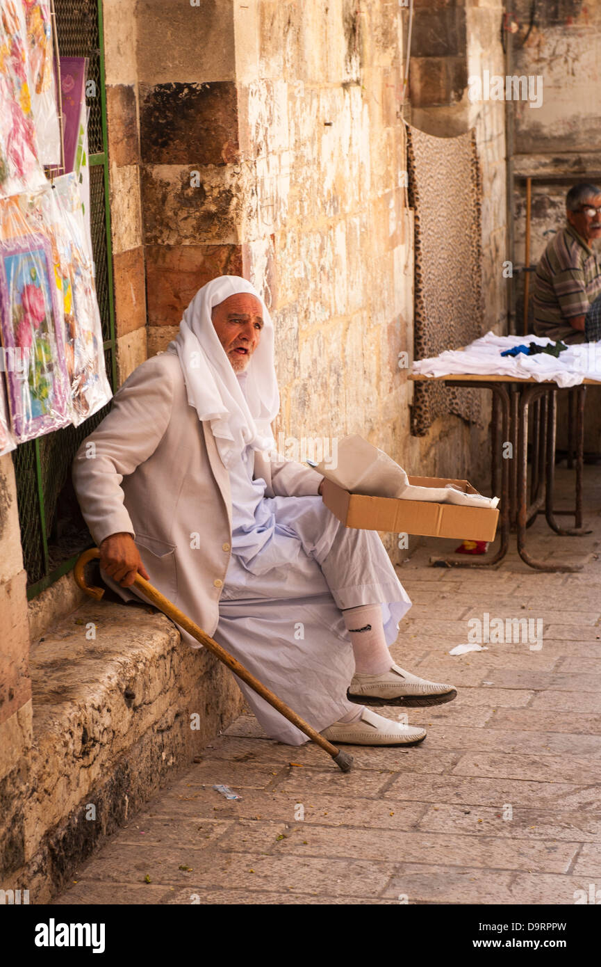 Israel , Jerusalem Old City , Muslim Arab Quarter , old man peddler vendor with keffiyeh ghurah shermagh & robe thwarb thobe Stock Photo