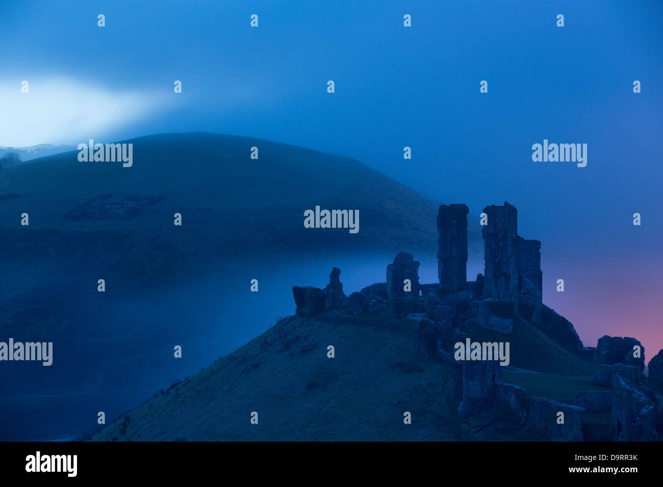 Corfe Castle in the mist at dawn, Dorset, England, UK Stock Photo