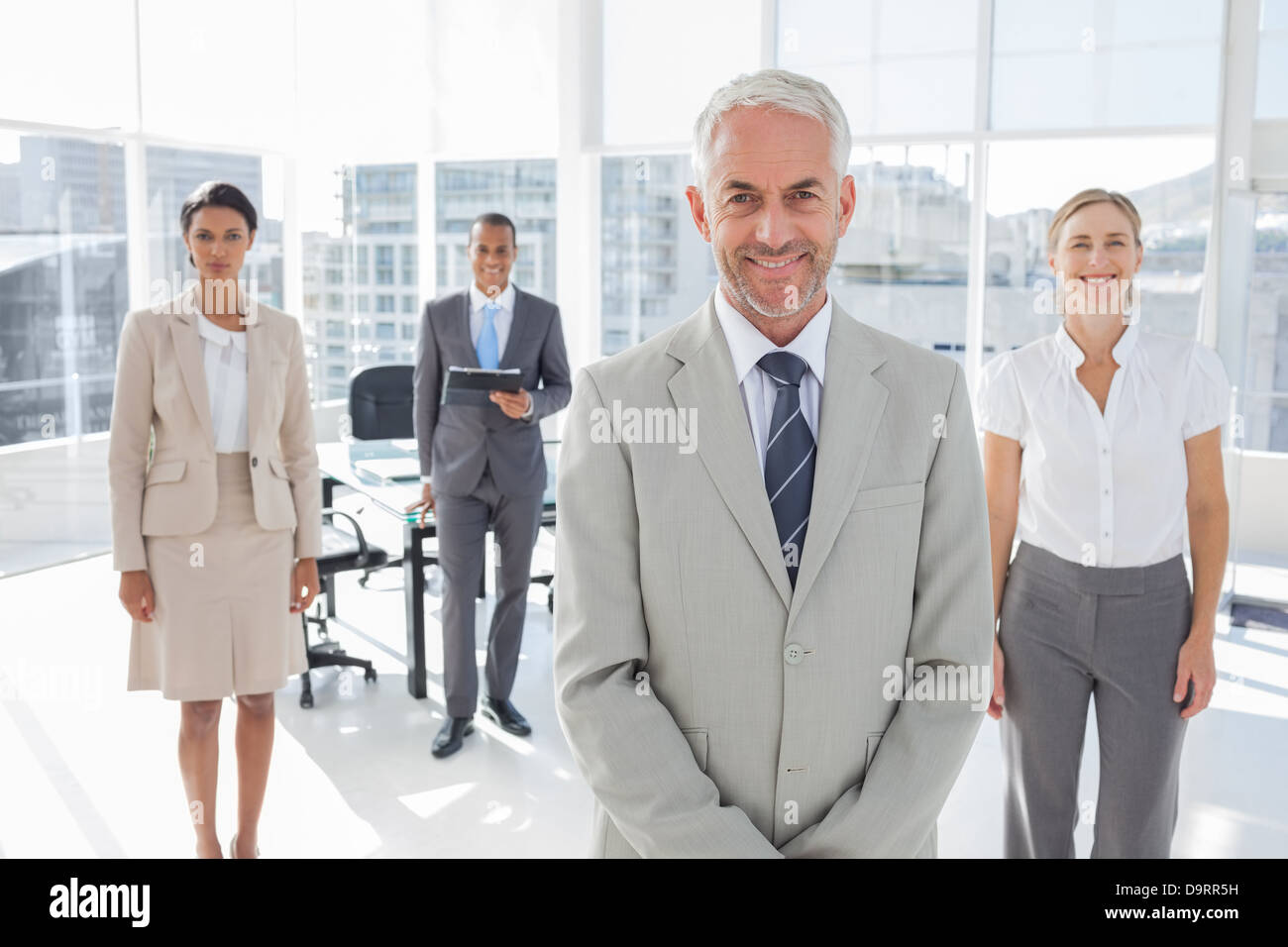 Serious businessman standing with colleagues Stock Photo - Alamy