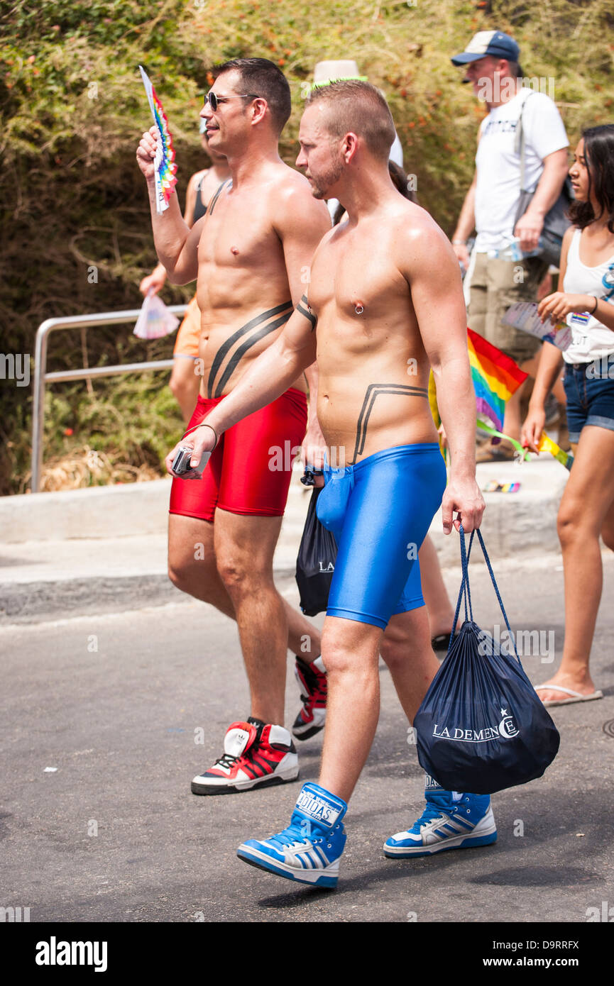 Israel Tel Aviv Gay Pride Day celebrations parade two 2 young boys men walking Lycra trunks to Gordon Beach party parade march pageant street scene Stock Photo