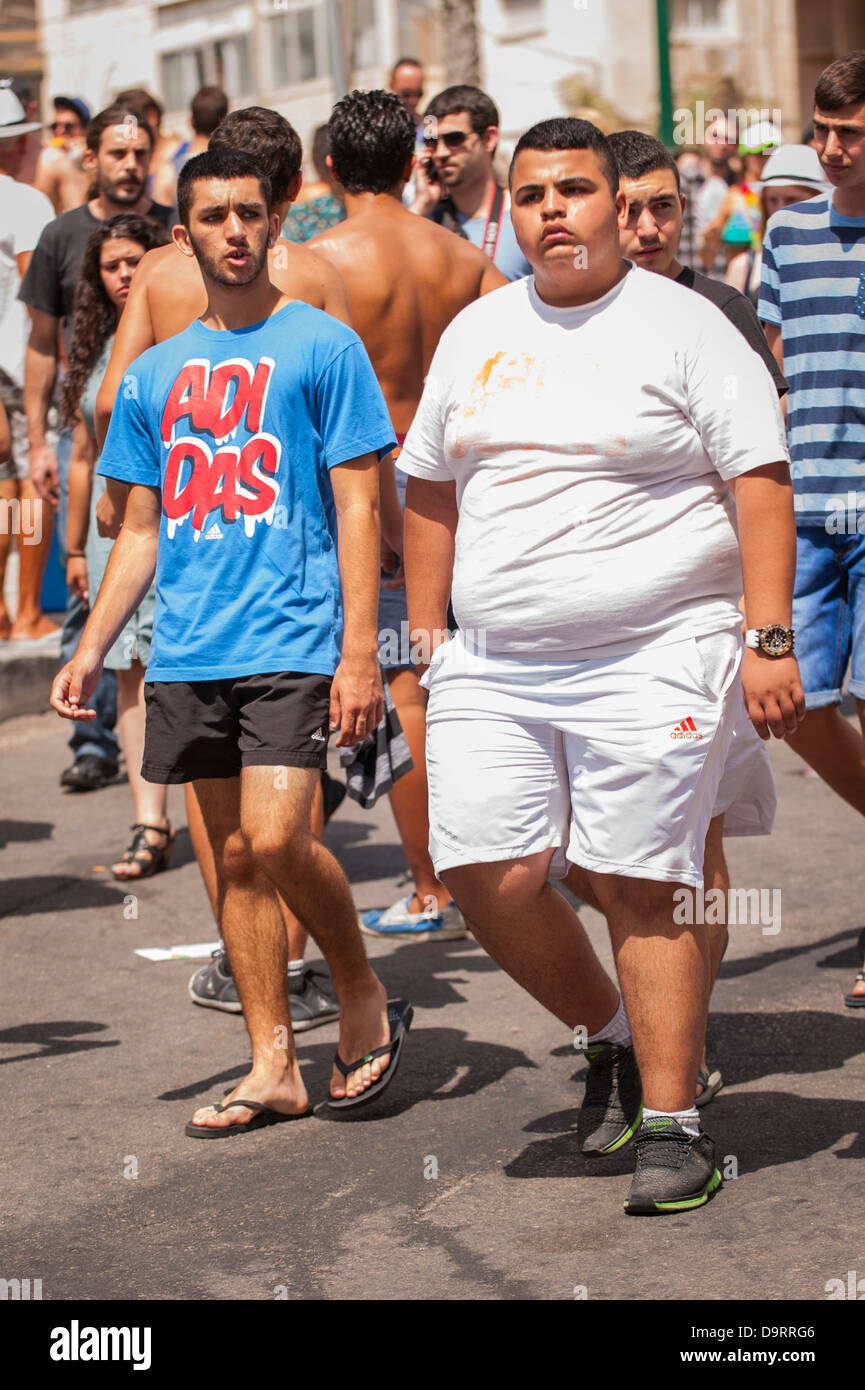 Israel Tel Aviv Gay Pride Day celebrations parade big fat boy walking with little thin skinny boy crowd sunny chatting Stock Photo